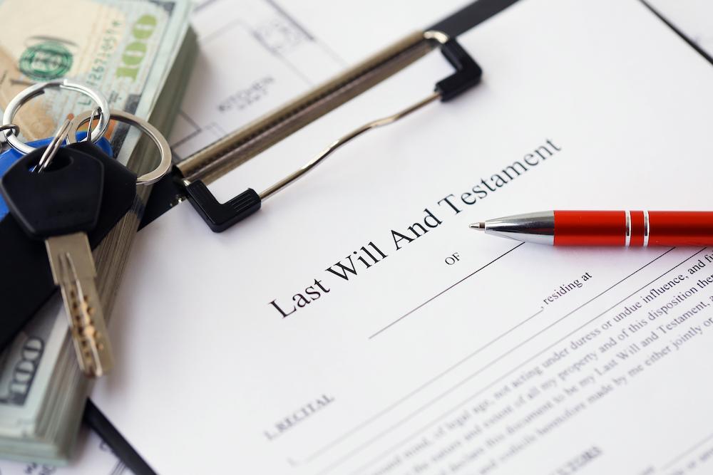 Last Will and Testament document on a clipboard with cash and keys, illustrating estate planning and asset inheritance.